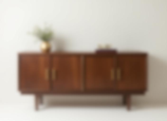 A modern walnut credenza with minimalist brass handles.